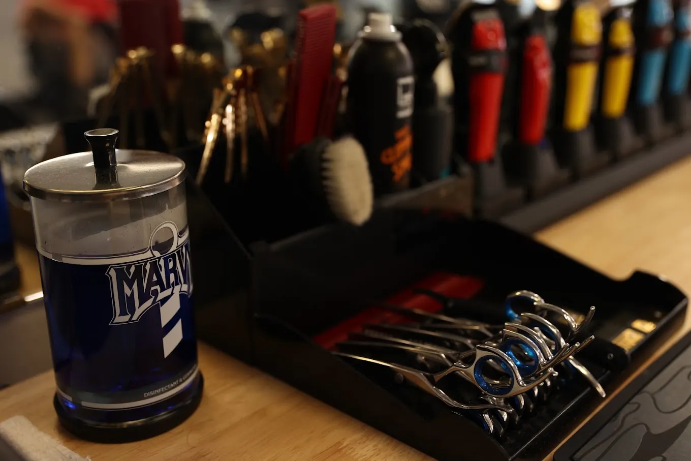 Barber tools at The Garage: shears, combs, clippers and a Marvy disinfectant jar on the counter